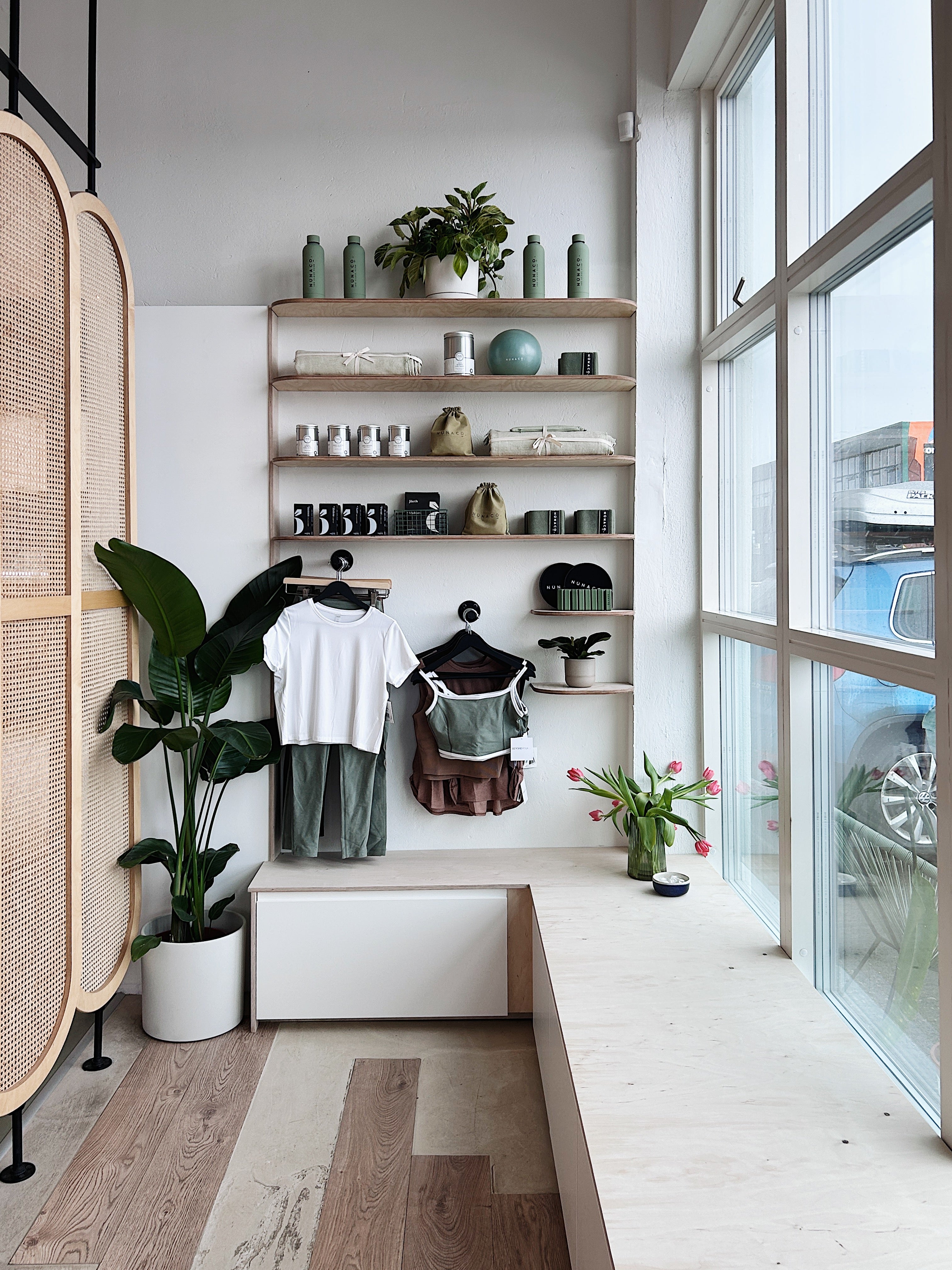 Modern interior with shelves, plants, and clothing in a well-lit room.